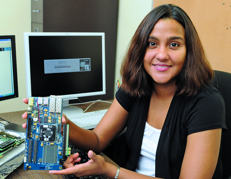 Marianne Hromalik, assistant professor of computer science, displays a computer circuit board that includes a detector (bottom right gray rectangle) of the type used to capture and store X-ray data used in scientific research.